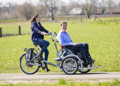 Location de vélos en Normandie : une femme fait du vélo adapté avec un passager sur une voie champêtre.