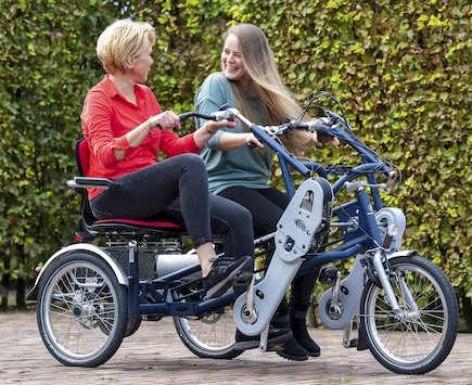 Deux femmes souriantes sur un vélo adapté à deux places, prêtes pour une balade. Location de vélos en Normandie par Roulez JEUnesse Loisirs.
