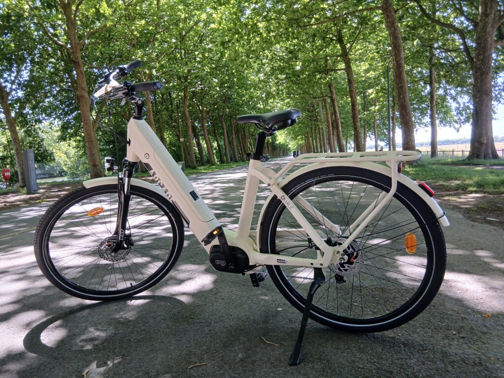 Vélo électrique en location sur une voie verte, entouré d'arbres, idéal pour des balades en famille ou entre amis en Normandie.