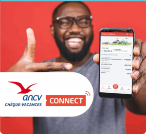 Homme souriant montrant son smartphone avec l'application Chèque-Vacances, arrière-plan rouge.